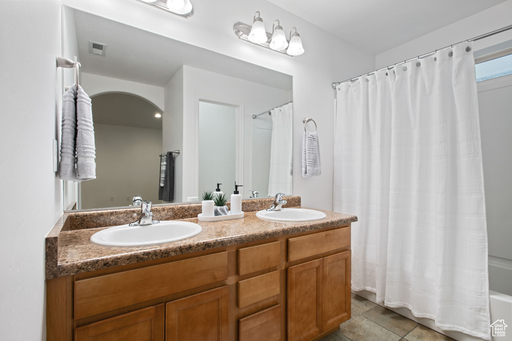 Bathroom with double vanity, visible vents, tile patterned flooring, and a sink