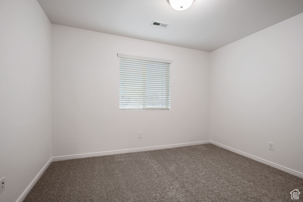 Empty room featuring baseboards, visible vents, and carpet floors