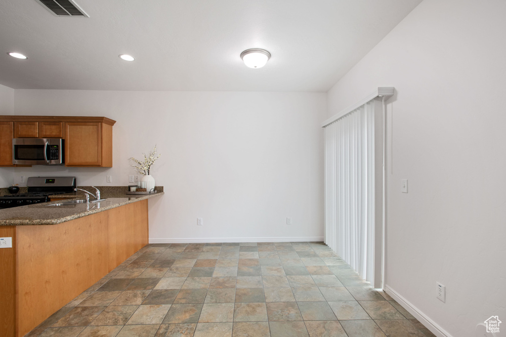 Kitchen with baseboards, visible vents, dark stone countertops, and stainless steel appliances