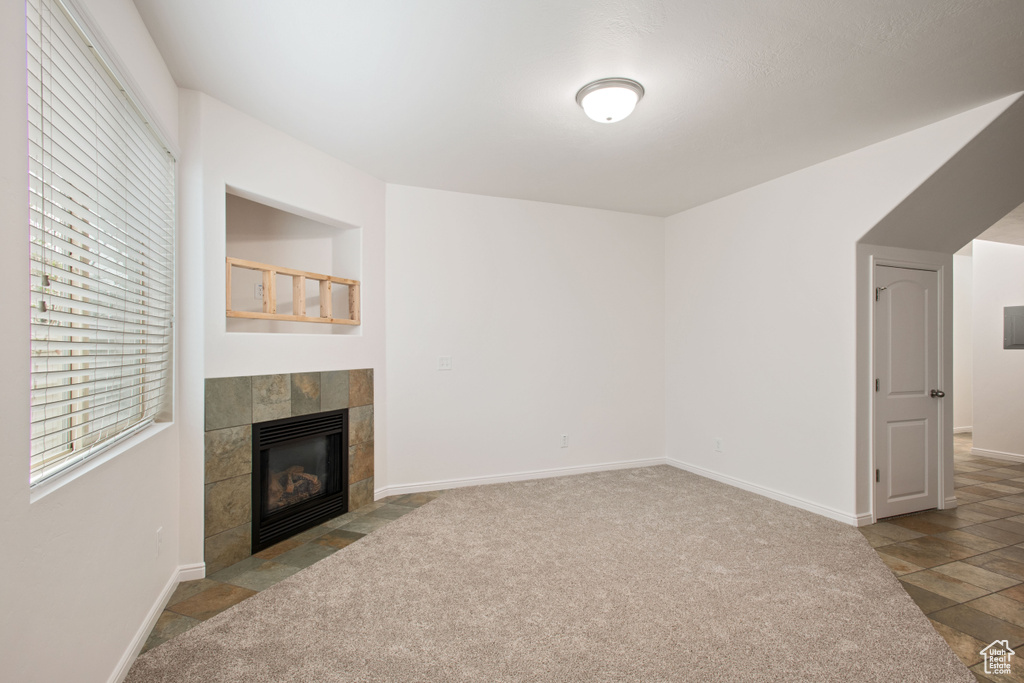 Unfurnished living room with carpet floors, baseboards, and a fireplace