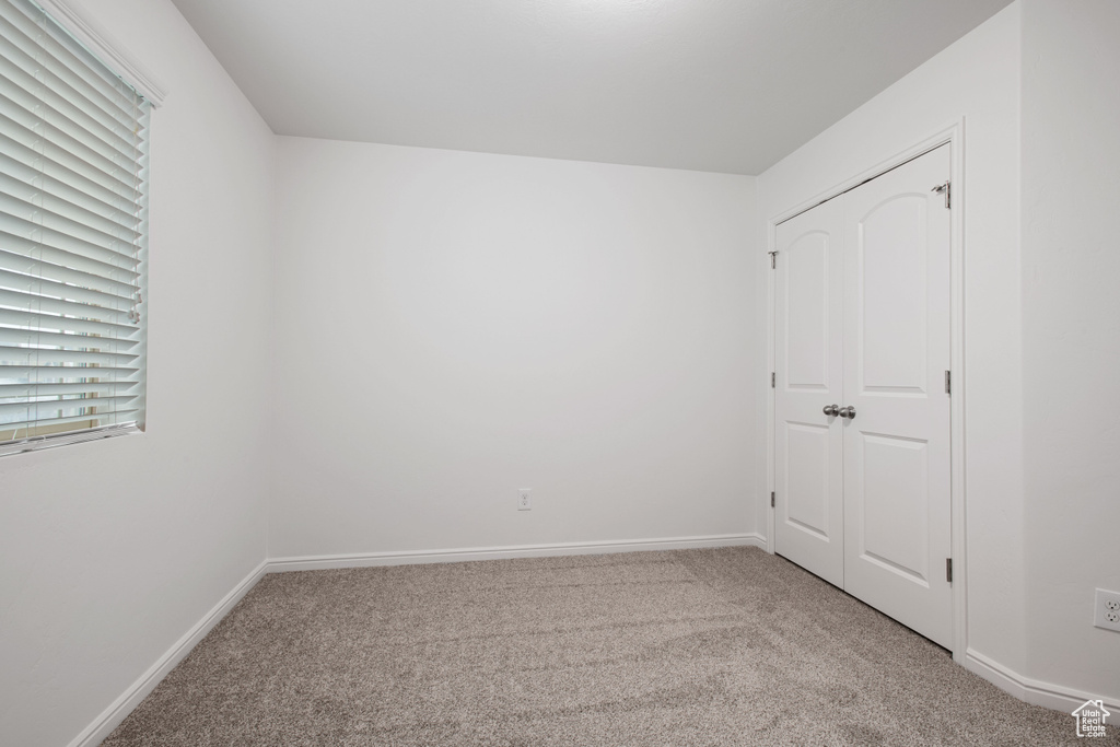 Unfurnished bedroom featuring light carpet and baseboards