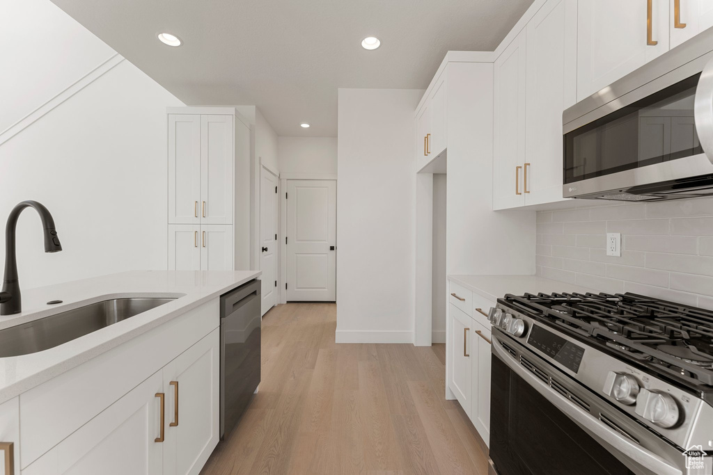 Kitchen featuring appliances with stainless steel finishes, light countertops, backsplash, and recessed lighting