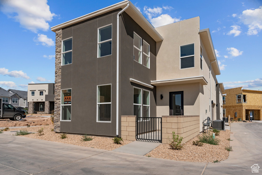 View of front facade featuring stucco siding, a gate, and stone siding