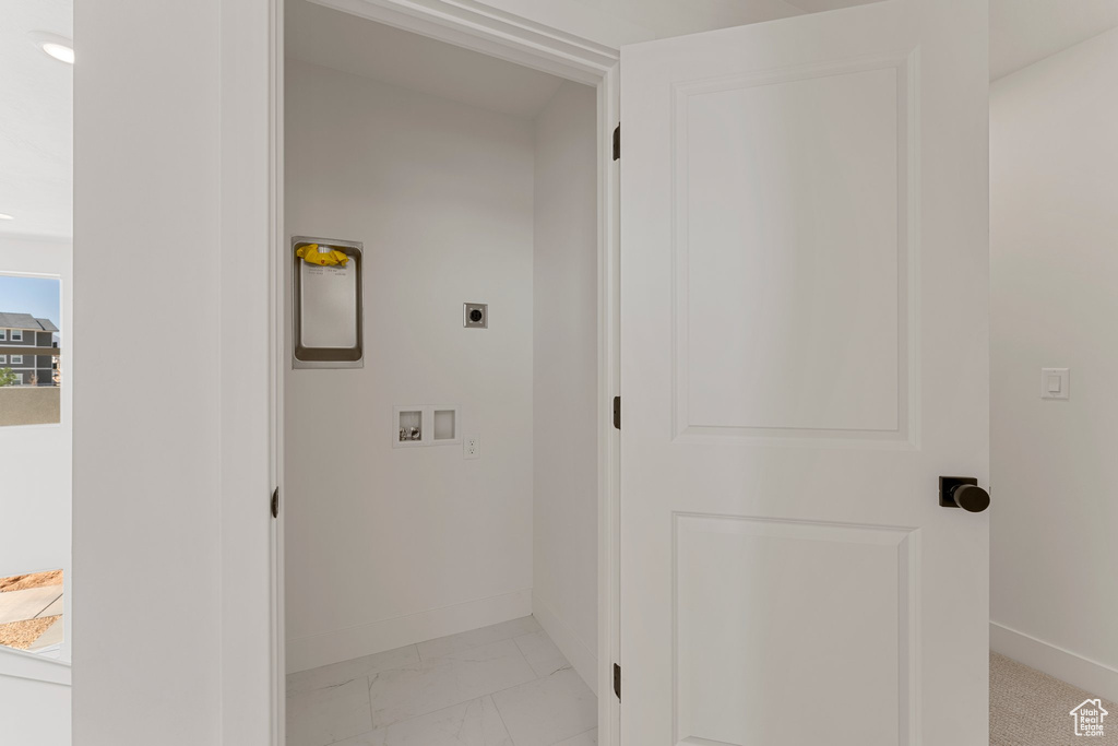 Laundry area featuring hookup for an electric dryer, hookup for a washing machine, and light marble finish flooring