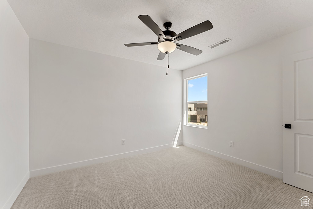 Empty room featuring a ceiling fan and light colored carpet