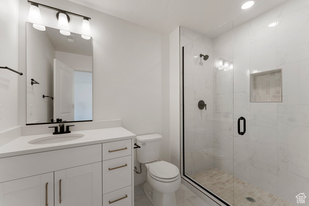 Full bath with marble look tile flooring, a stall shower, and vanity