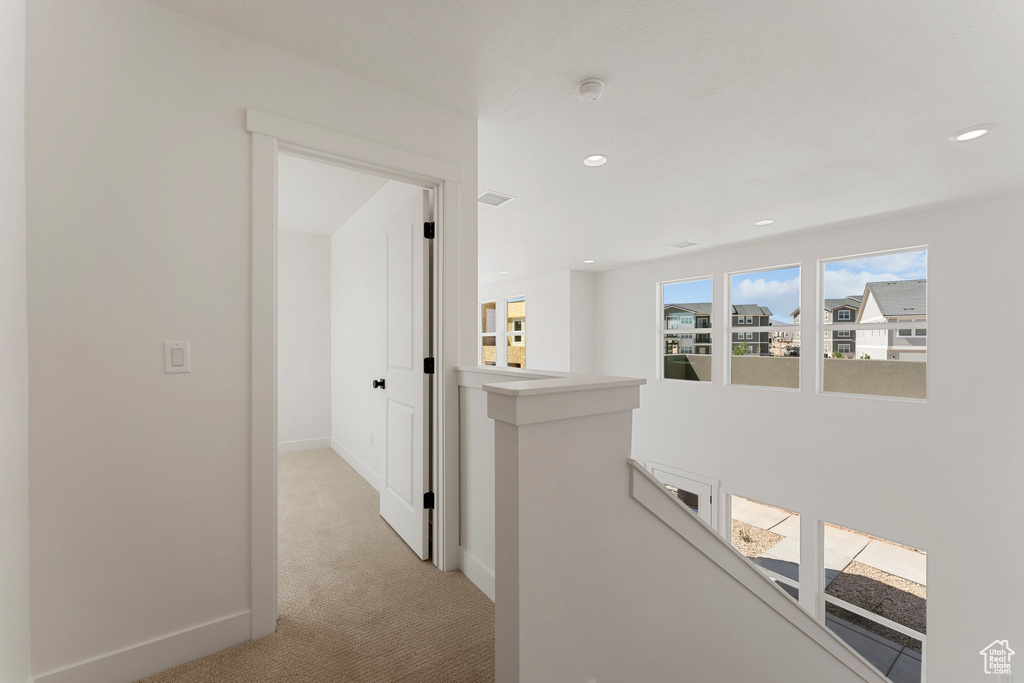 Hall with an upstairs landing, light carpet, and recessed lighting