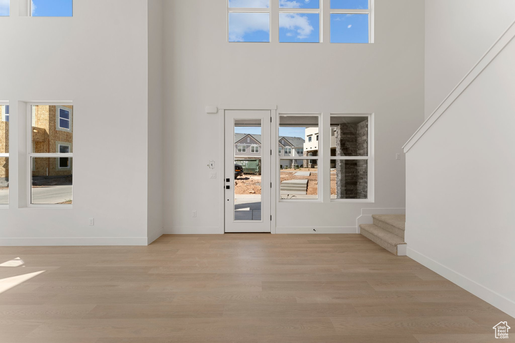 Entryway featuring a high ceiling, light wood-type flooring, and stairs
