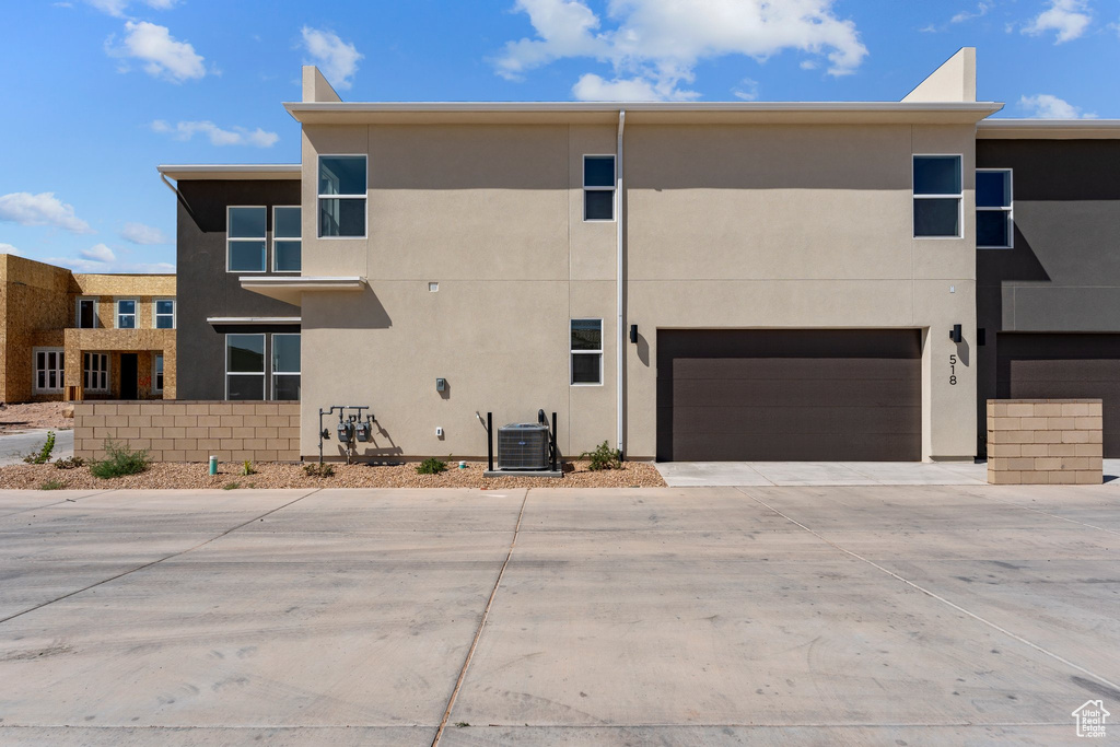 Back of house featuring stucco siding, concrete driveway, and an attached garage