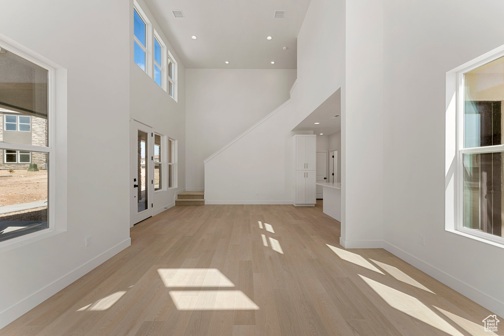 Foyer with a towering ceiling, light wood-style flooring, and recessed lighting