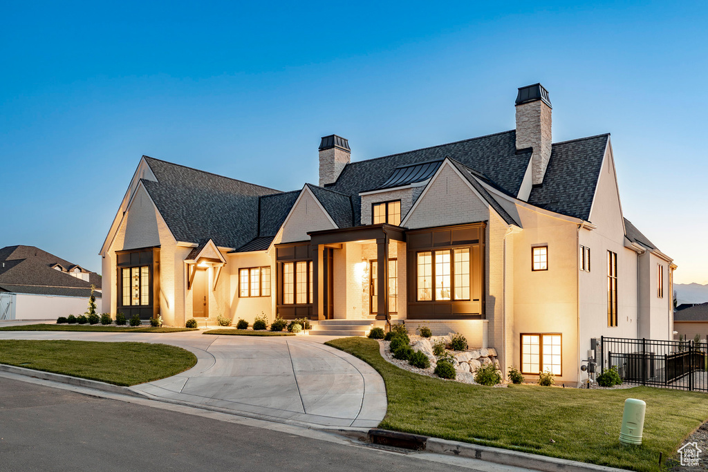 Modern farmhouse with a chimney, a standing seam roof, curved driveway, and metal roof