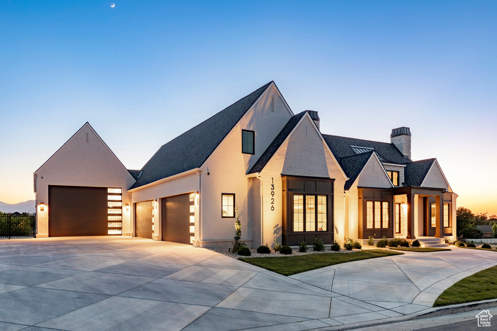 View of front of property featuring concrete driveway, a chimney, a garage, stucco siding, and a shingled roof