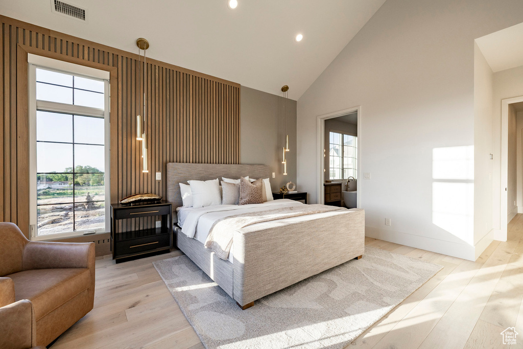 Bedroom featuring high vaulted ceiling, light wood-style flooring, recessed lighting, connected bathroom, and baseboards