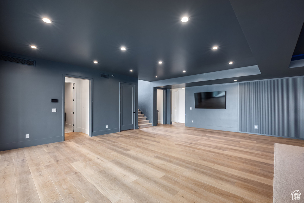 Unfurnished living room featuring visible vents, recessed lighting, light wood-style flooring, and stairway