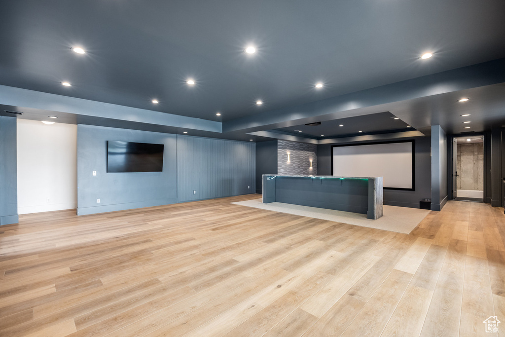 Cinema with recessed lighting, light wood-style floors, and a raised ceiling