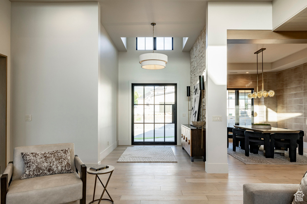 Entrance foyer with light wood-style floors, a high ceiling, a chandelier, and baseboards