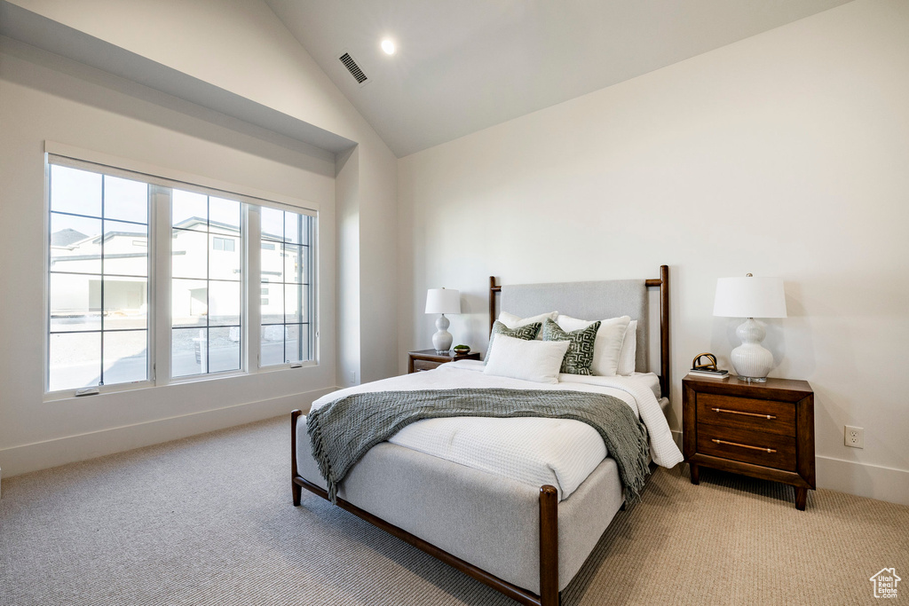 Bedroom featuring light carpet, lofted ceiling, and baseboards