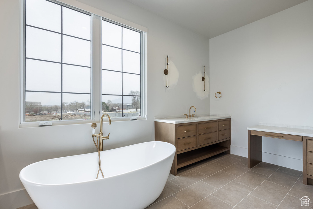 Full bathroom featuring a freestanding tub, tile patterned flooring, and vanity
