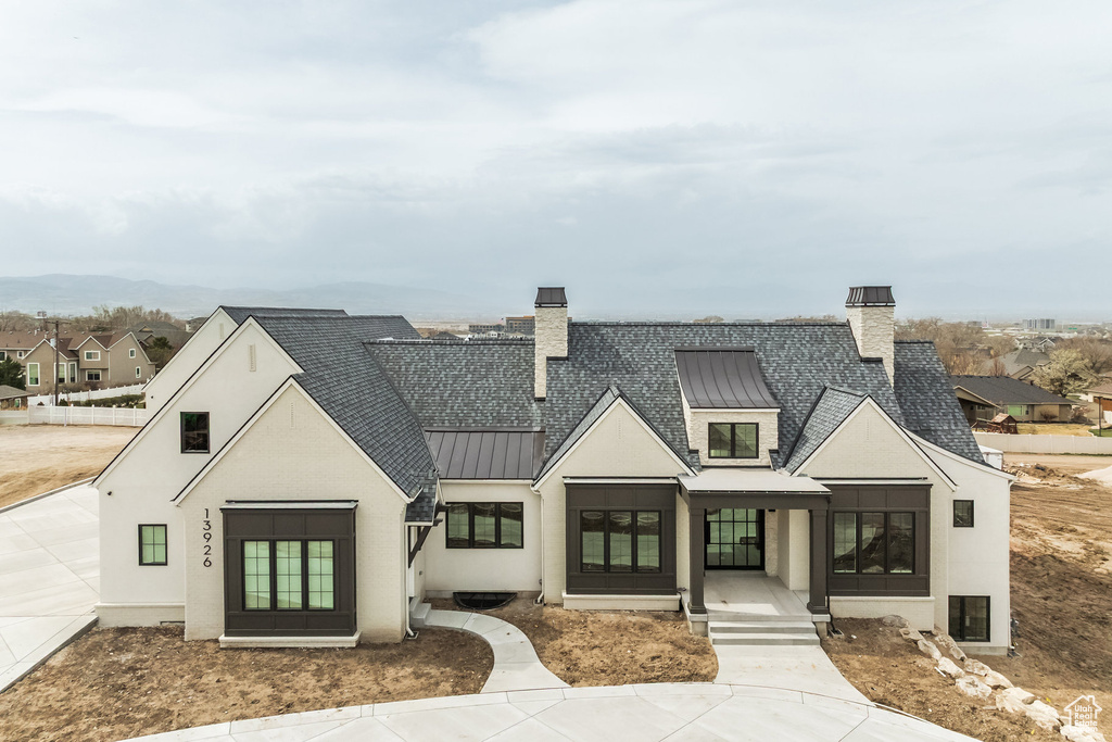 Modern farmhouse featuring metal roof, a standing seam roof, a chimney, and roof with shingles