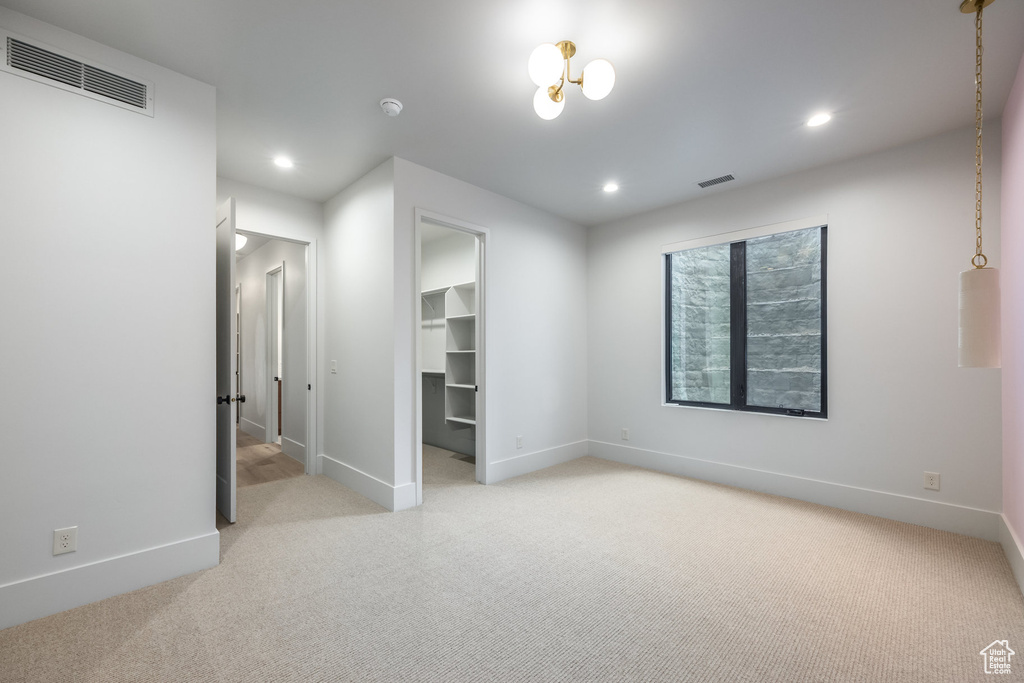 Unfurnished bedroom featuring recessed lighting, a spacious closet, baseboards, visible vents, and light carpet