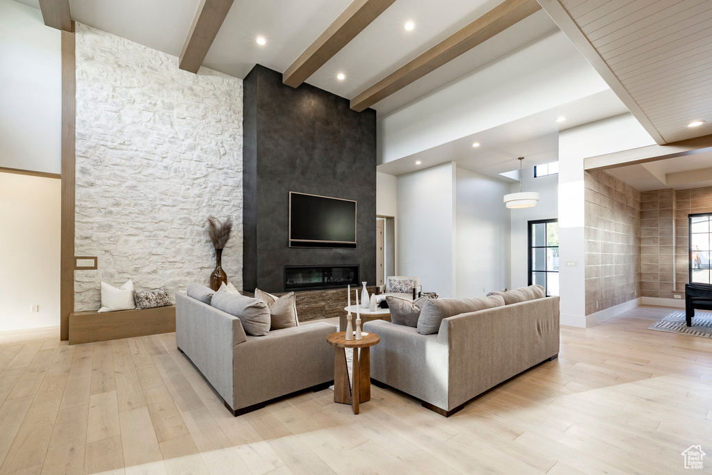 Living area with beam ceiling, light wood finished floors, a towering ceiling, baseboards, and recessed lighting