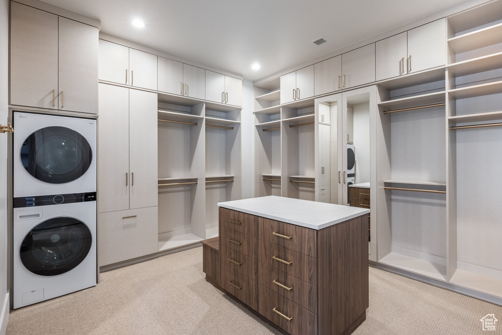 Walk in closet with visible vents, stacked washer / drying machine, and light colored carpet