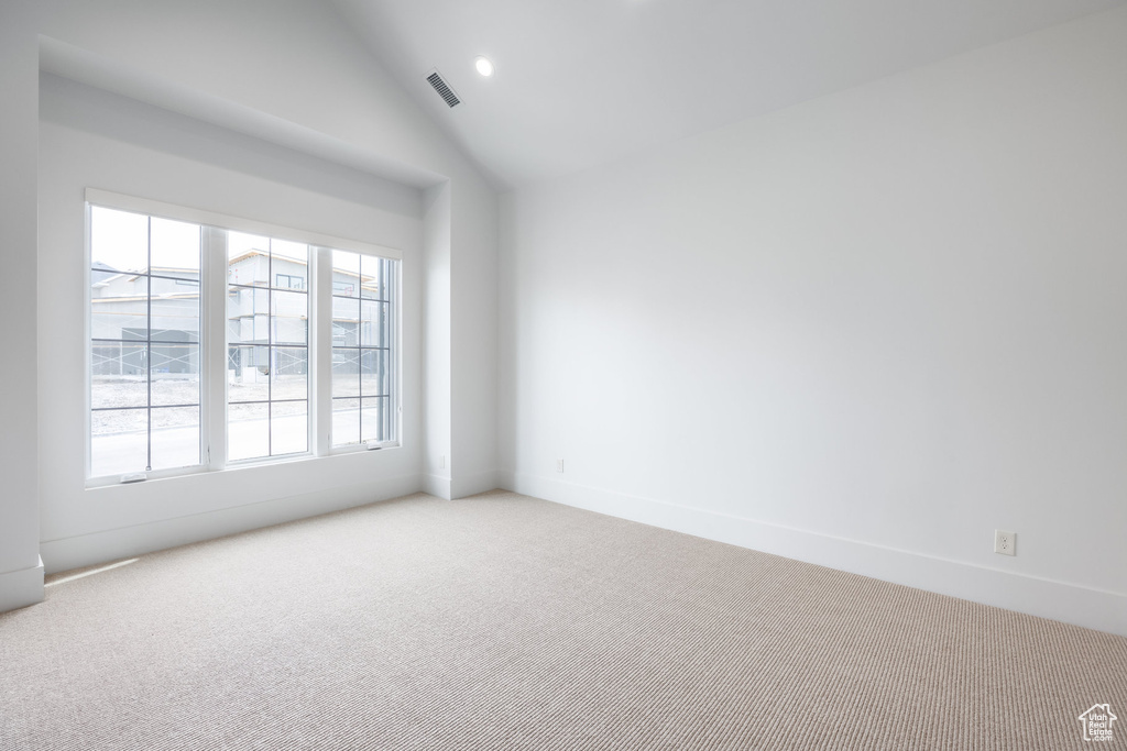 Empty room with lofted ceiling, recessed lighting, baseboards, visible vents, and light carpet