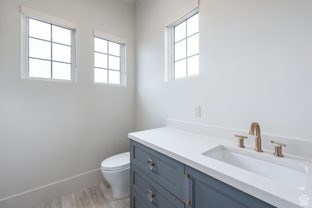 Bathroom featuring baseboards, wood finished floors, toilet, and vanity