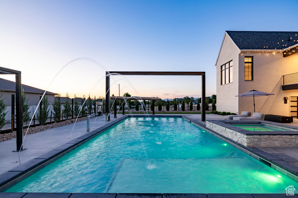 Outdoor pool featuring an in-ground hot tub and a patio area