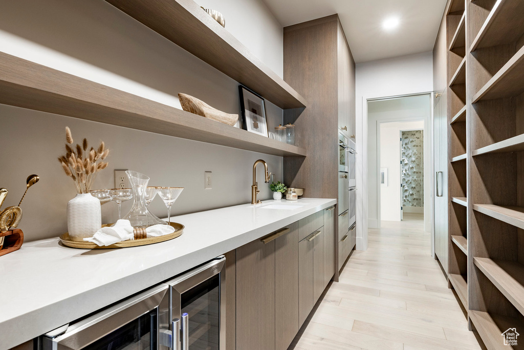 Indoor wet bar featuring beverage cooler and light wood-style flooring