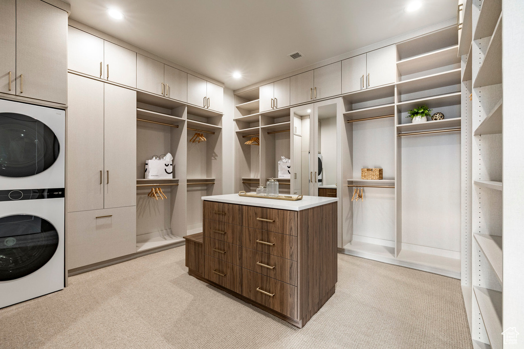 Walk in closet featuring stacked washer / drying machine and light colored carpet