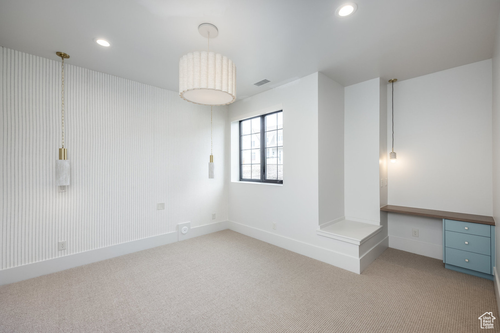 Spare room with built in study area, recessed lighting, light carpet, and visible vents