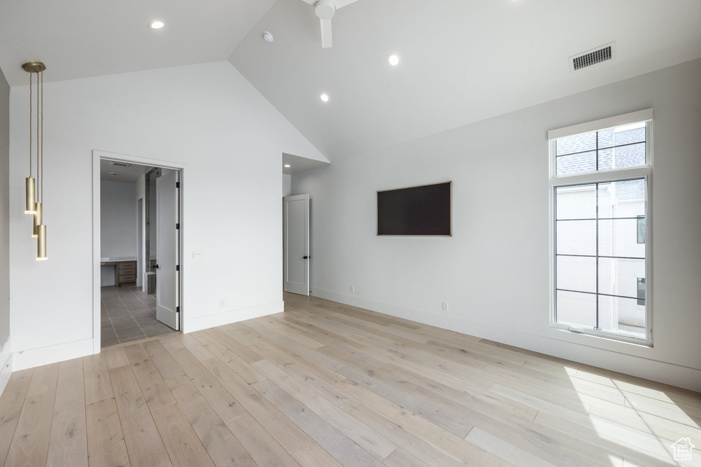 Unfurnished living room with high vaulted ceiling, visible vents, baseboards, recessed lighting, and light wood-style floors