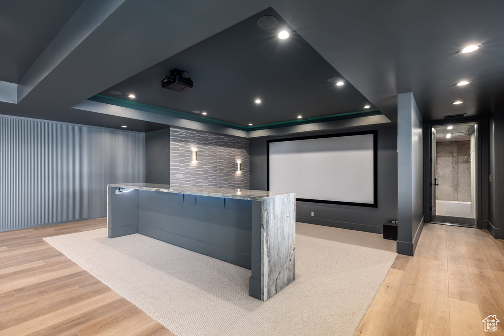 Home theater room featuring a tray ceiling, recessed lighting, and light wood finished floors