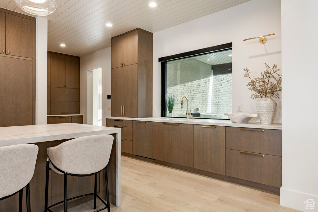 Kitchen with light wood-type flooring, recessed lighting, light countertops, modern cabinets, and a sink
