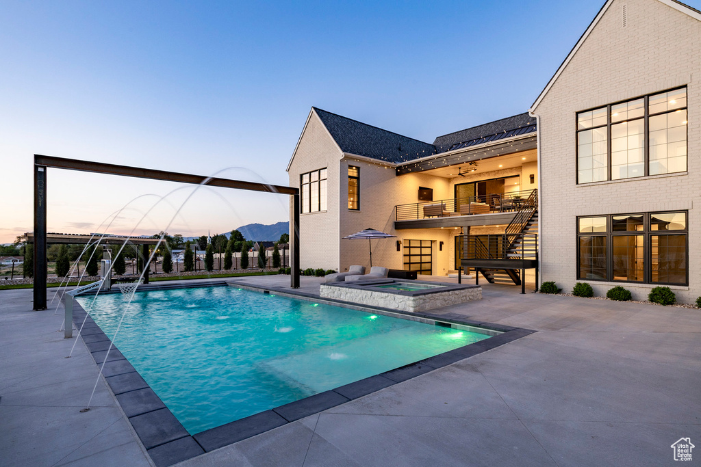 Outdoor pool with stairs, a patio area, an in-ground hot tub, and a ceiling fan