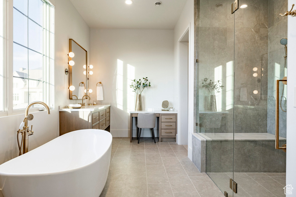 Bathroom featuring vanity, a freestanding bath, a stall shower, tile patterned flooring, and baseboards