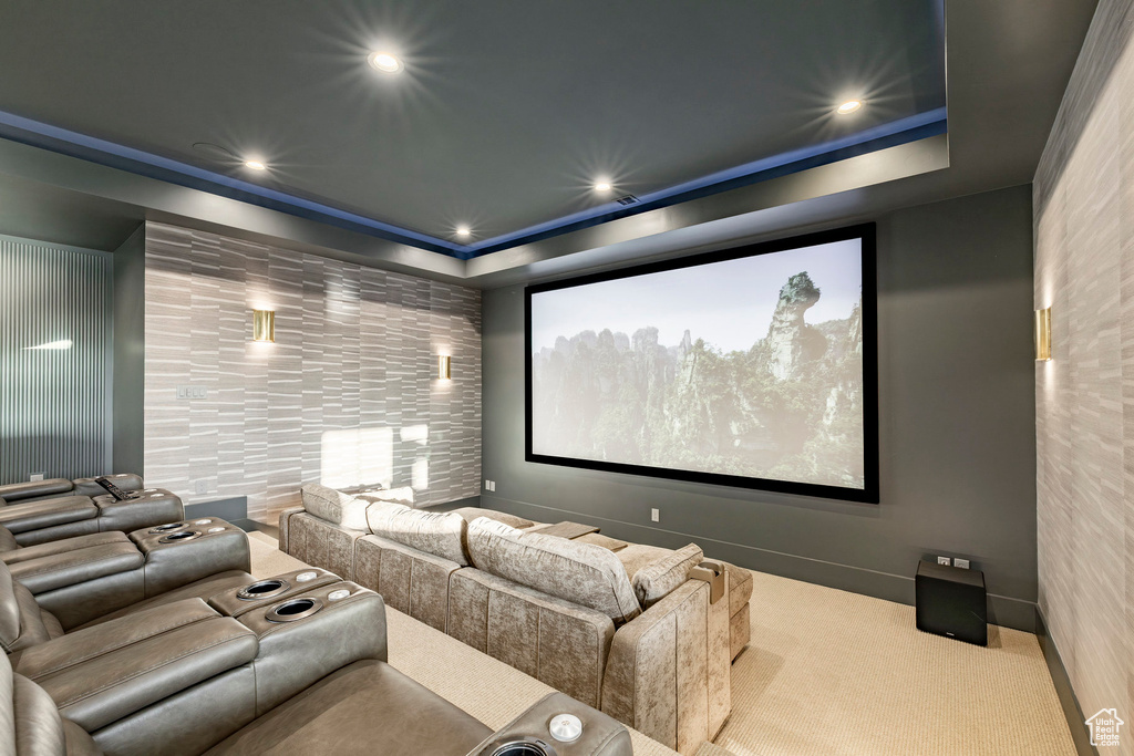 Carpeted cinema with a tray ceiling and recessed lighting