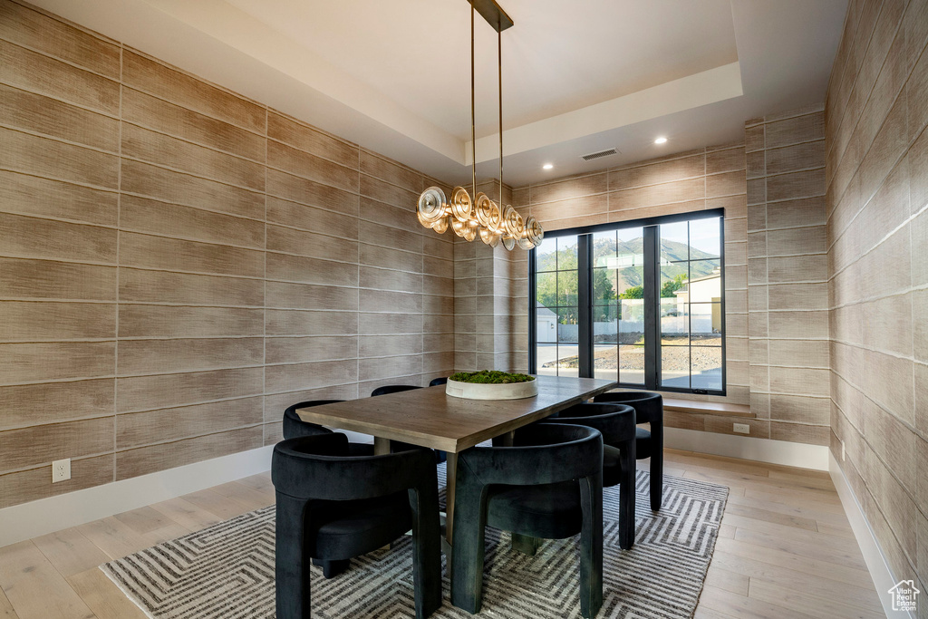 Dining area featuring a tray ceiling, light wood-style floors, a chandelier, and recessed lighting