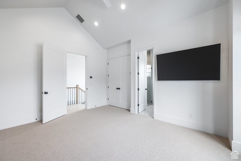 Unfurnished bedroom with recessed lighting, high vaulted ceiling, carpet floors, visible vents, and ensuite bathroom