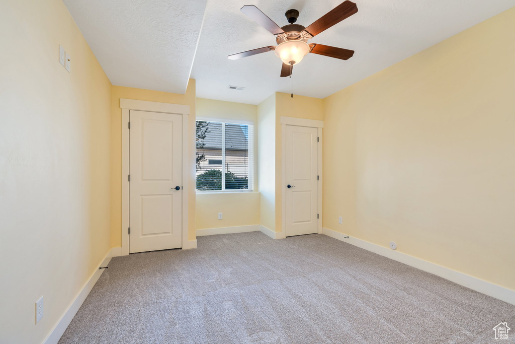 Unfurnished room with a ceiling fan, light carpet, and baseboards
