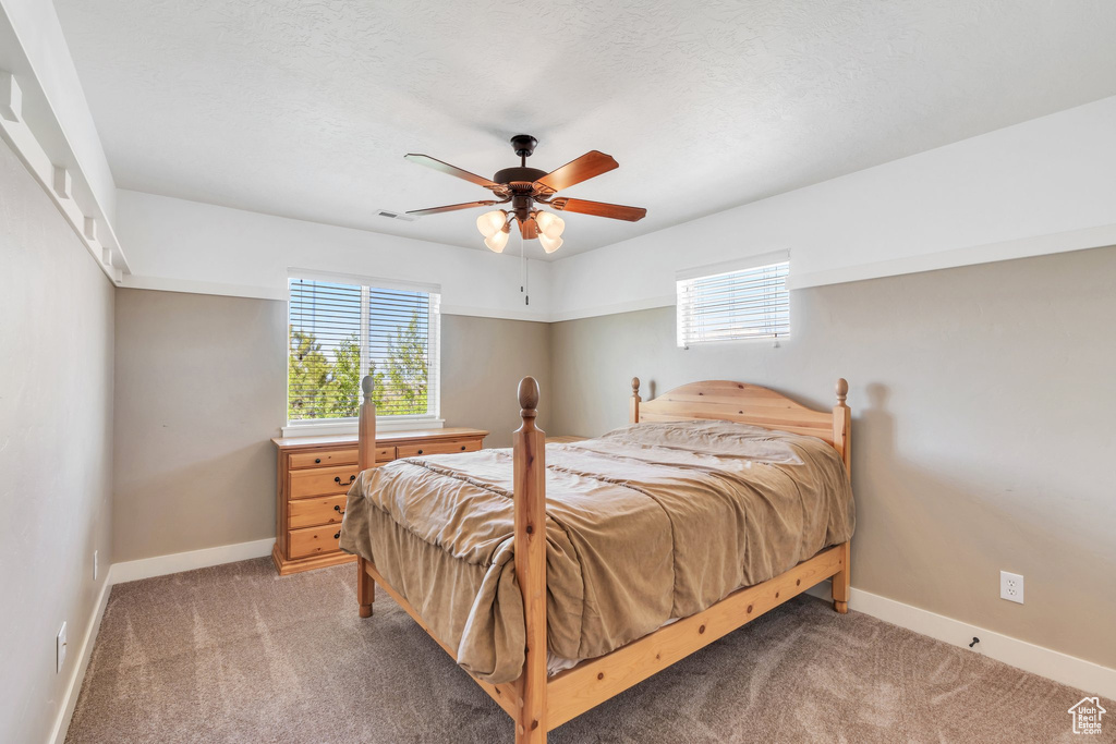 Bedroom featuring light colored carpet, baseboards, and a ceiling fan