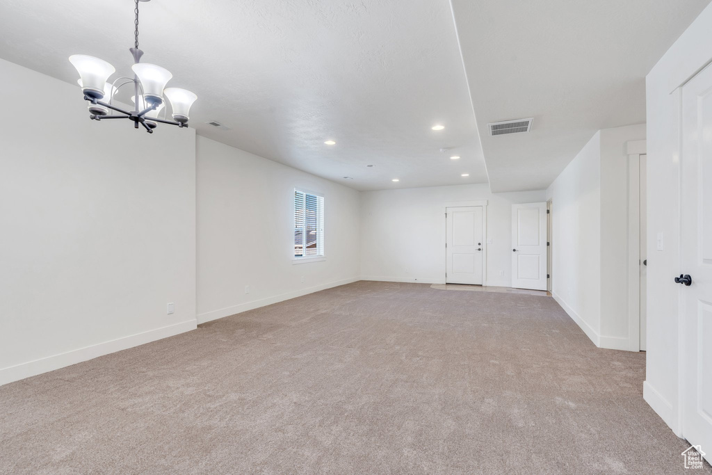 Carpeted spare room featuring a chandelier, recessed lighting, and baseboards