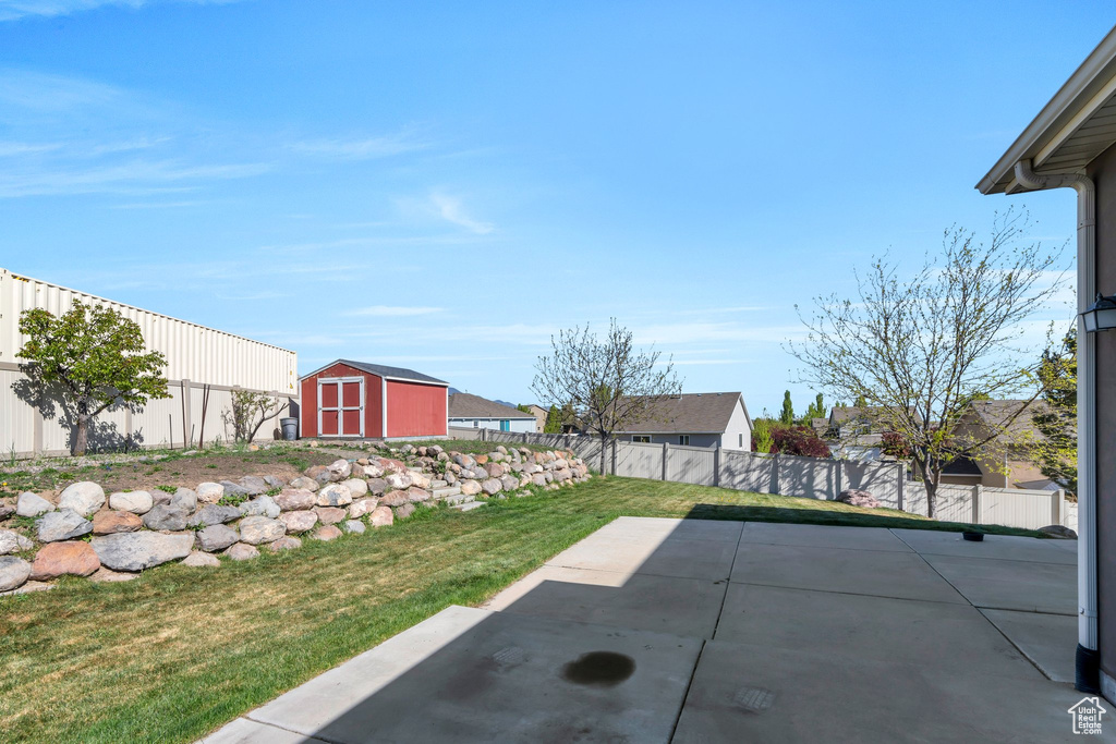 View of yard with an outdoor structure, a fenced backyard, a shed, and a patio area