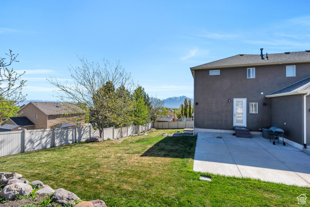 View of yard featuring a mountain view, a fenced backyard, entry steps, and a patio area