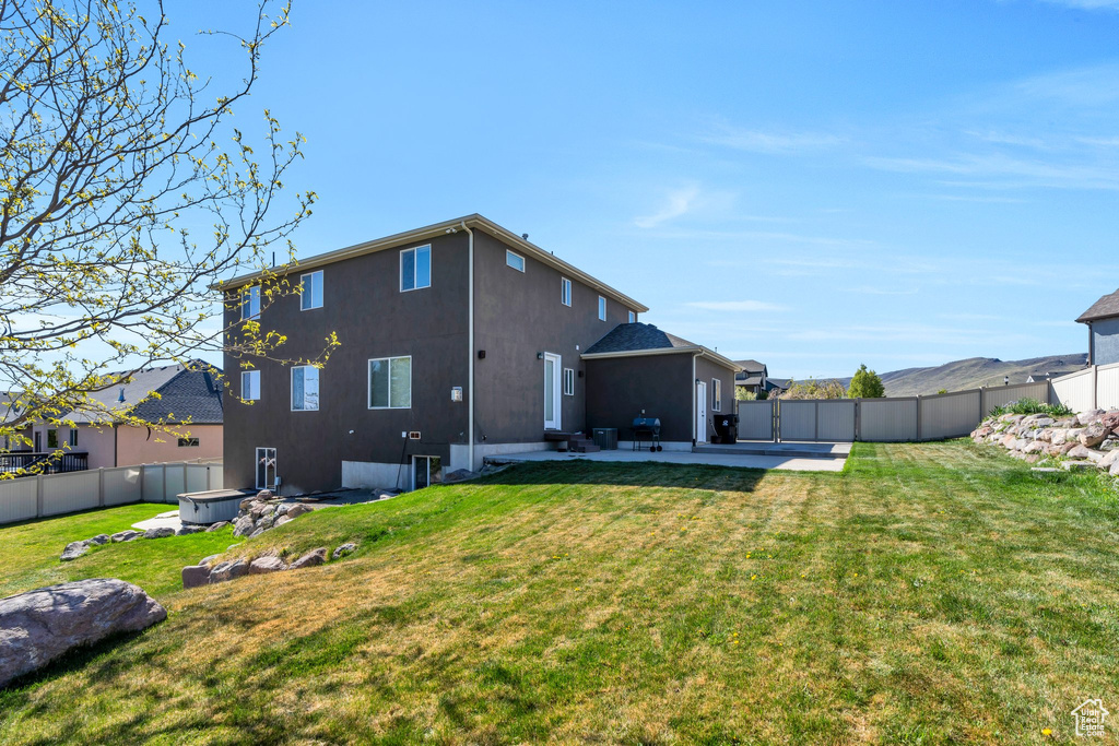Rear view of property featuring a patio, a fenced backyard, stucco siding, and a yard