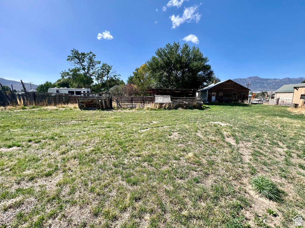 View of yard with an outbuilding, fence, a rural view, and a mountain view