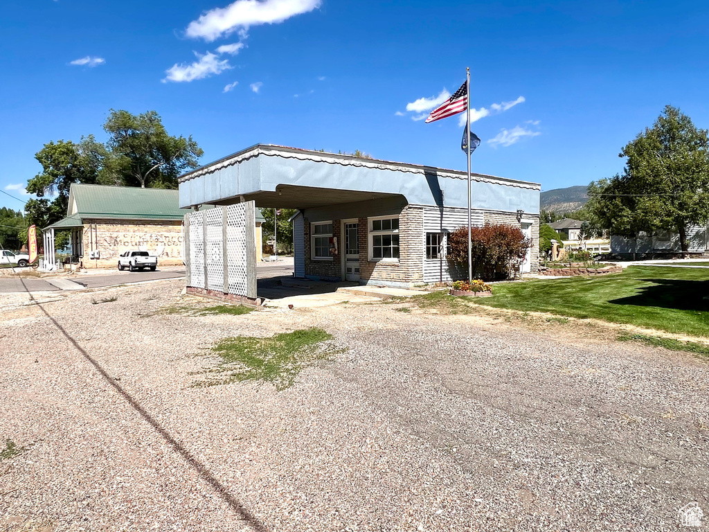 View of front of property with a front yard, gravel driveway, and a carport