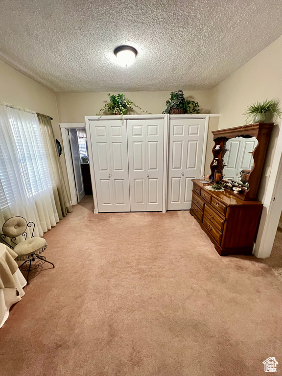 Bedroom featuring light carpet and a textured ceiling