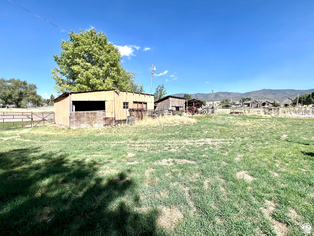 View of yard featuring an outbuilding, a mountain view, fence, and a rural view